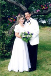 Wedding couple in front of flower bedecked apple tree